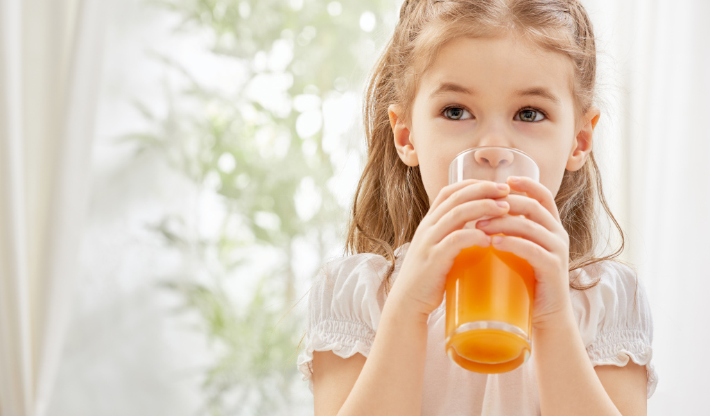 Маленькая девочка со стаканом сока в руках