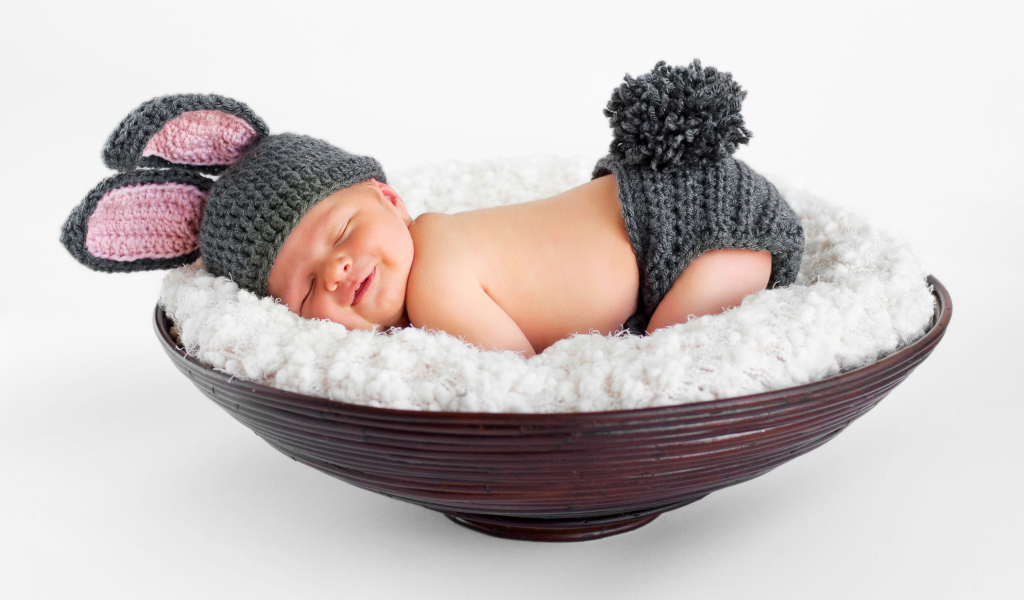 Маленький спящий грудной ребенок в вязаном костюме зайчика