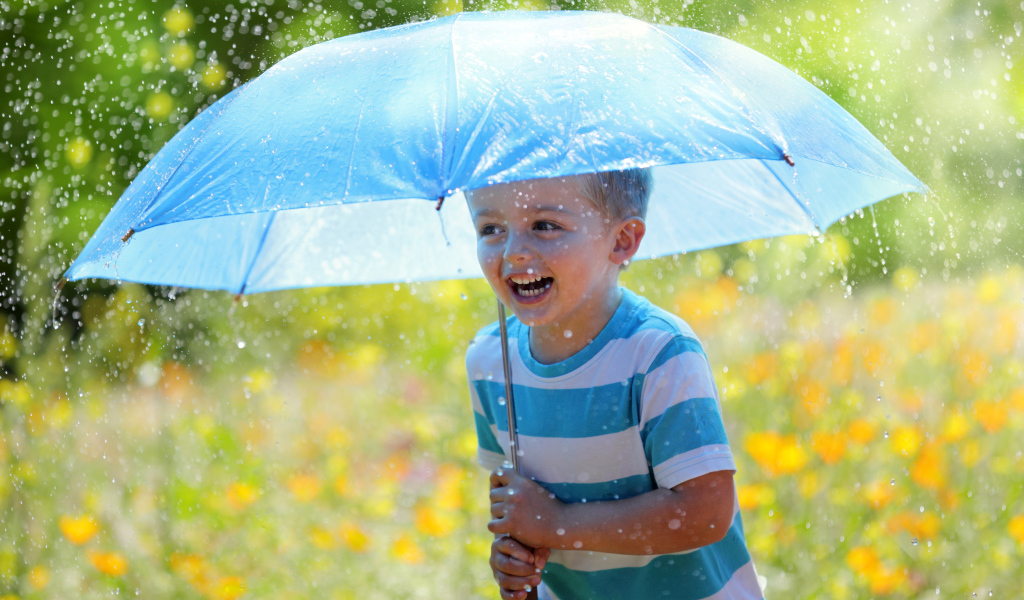Маленький улыбающийся мальчик с голубым зонтом под дождем