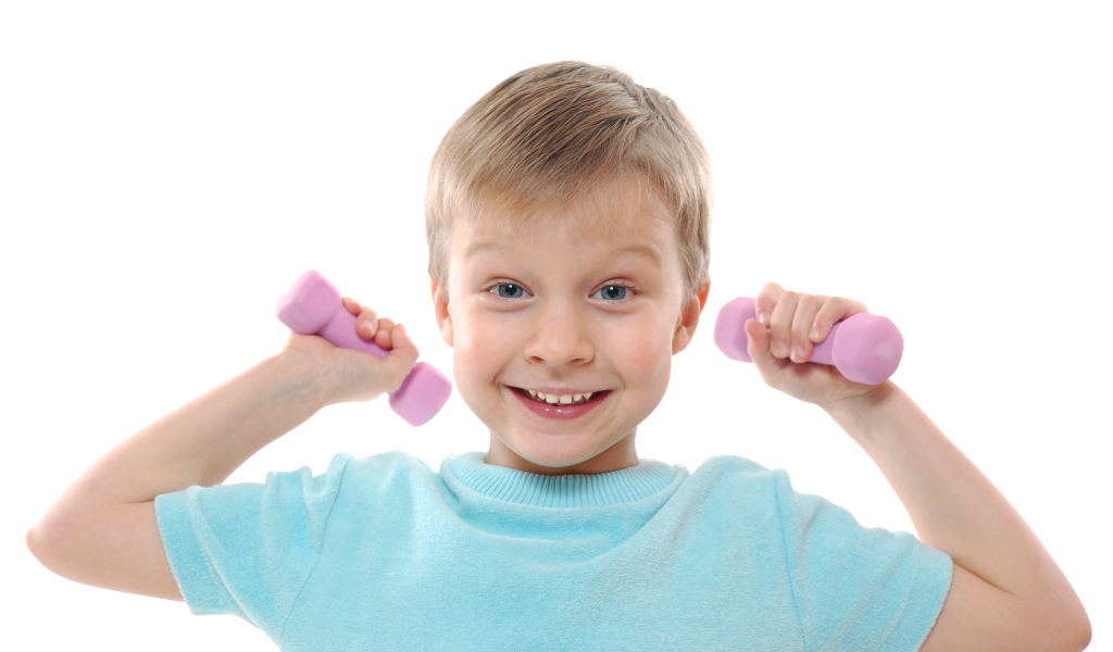 Маленький улыбающийся мальчик с гантелями на белом фоне