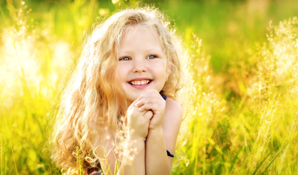 Маленькая улыбающаяся девочка в лучах солнца