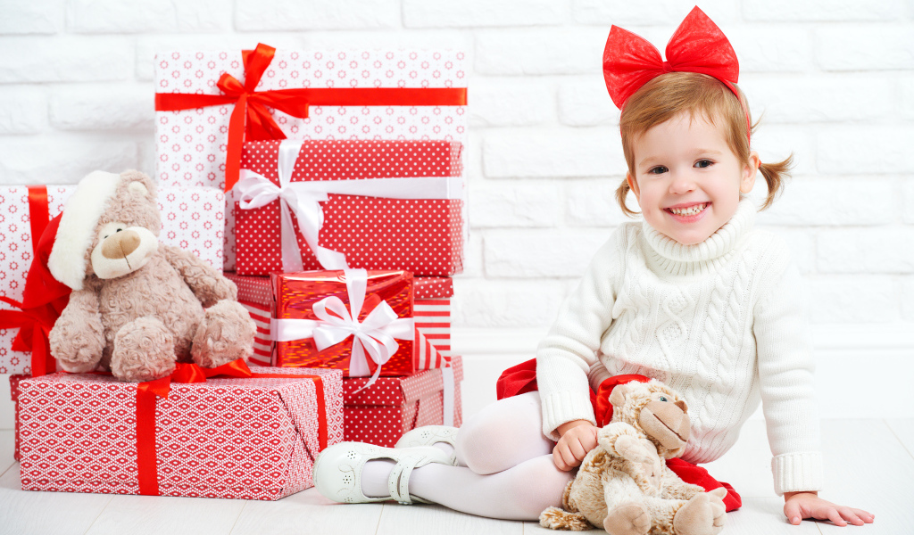 Маленькая улыбающаяся девочка с подарками на новый год