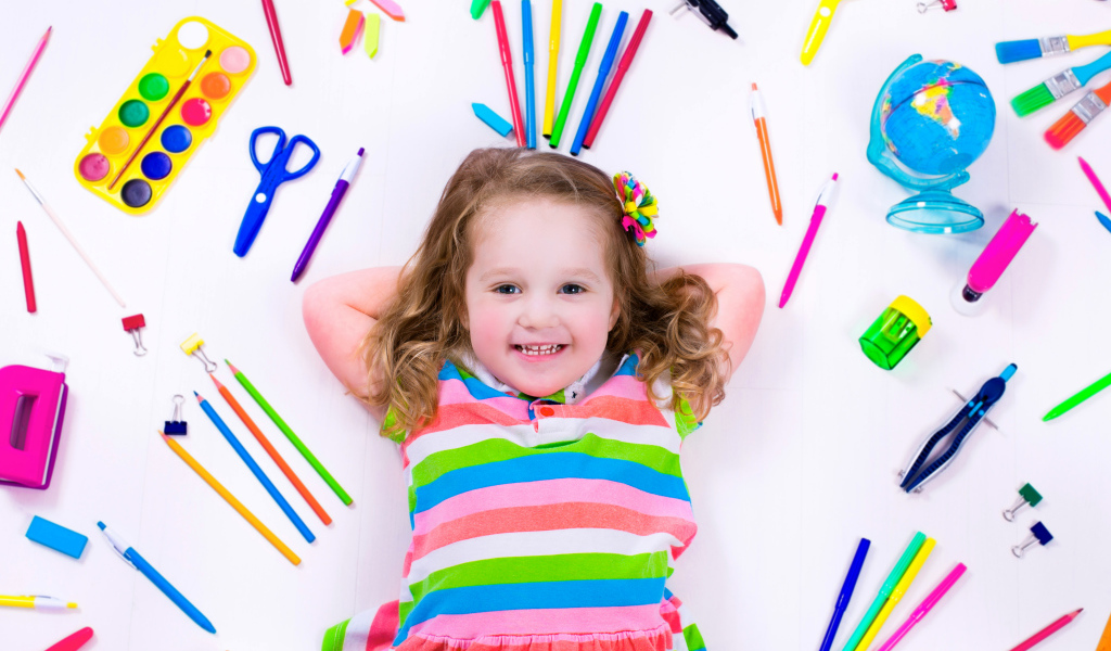 Маленькая улыбающаяся девочка со школьными принадлежностями