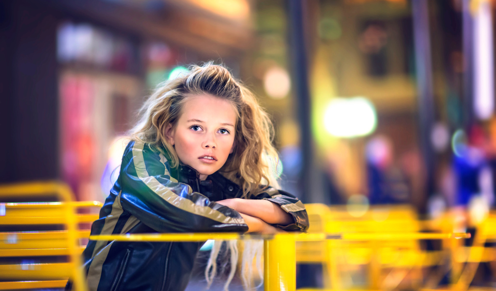 Длинноволосая девочка сидит на карусели