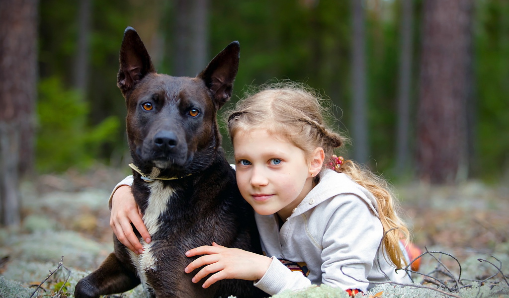 Милая голубоглазая девочка с большой черной собакой