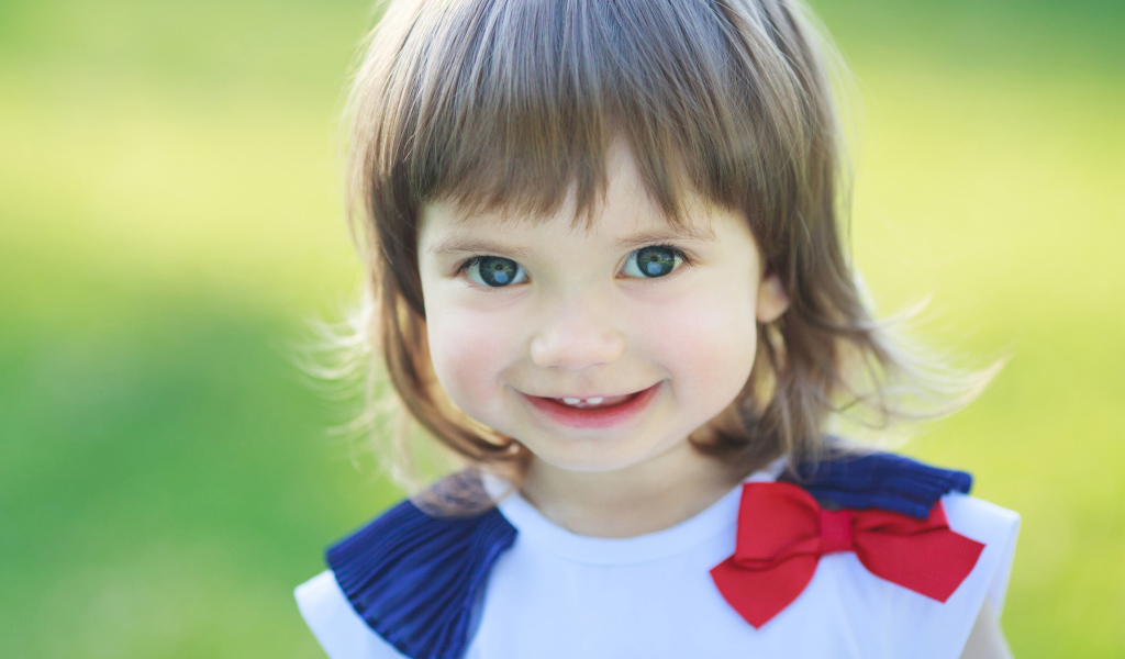 Милая улыбающаяся зеленоглазая маленькая девочка