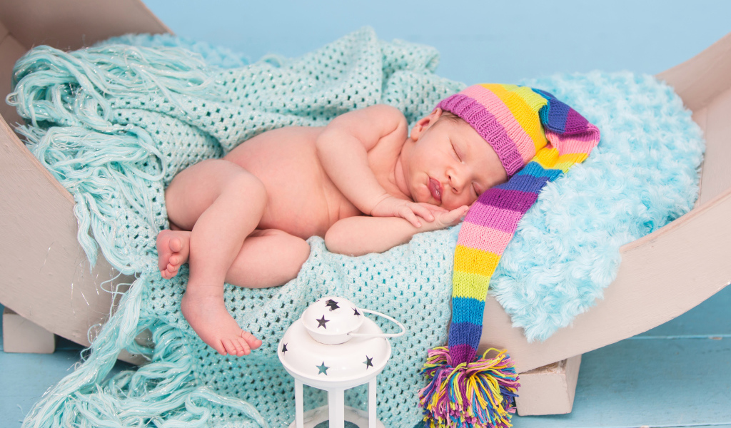 Спящий грудной ребенок в большой вязаной шапке