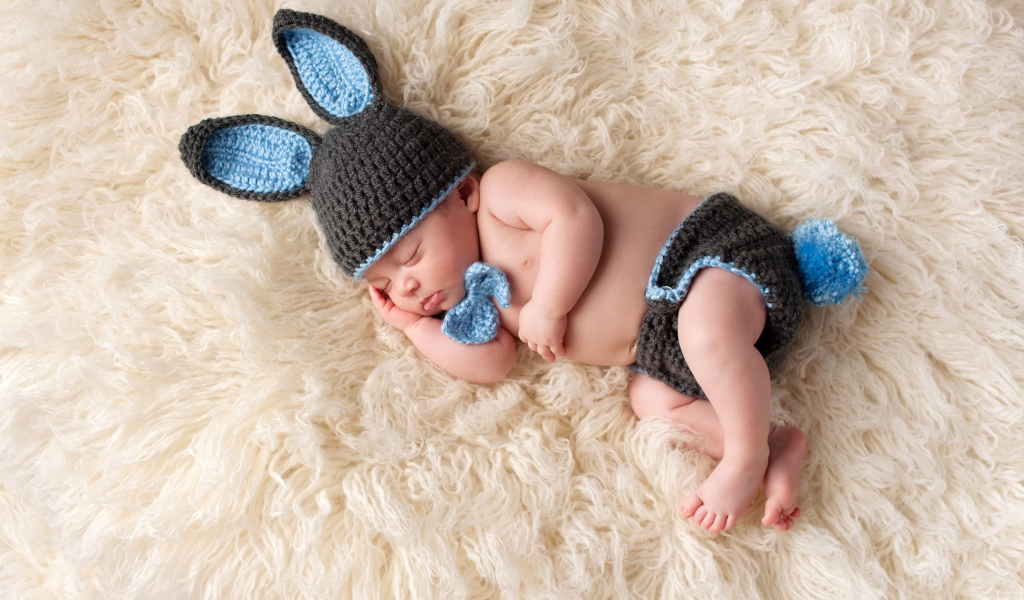 Спящий младенец в вязаном костюме зайца