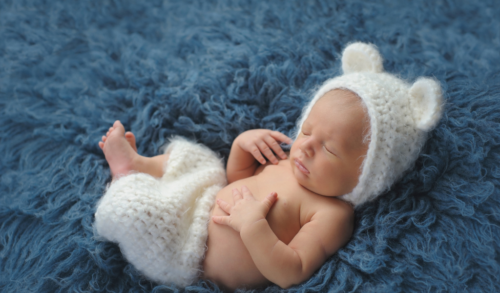 Спящий грудной ребенок в белом костюме медвежонка