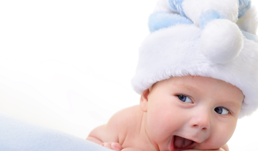 Улыбающийся грудной ребенок в голубой новогодней шапке
