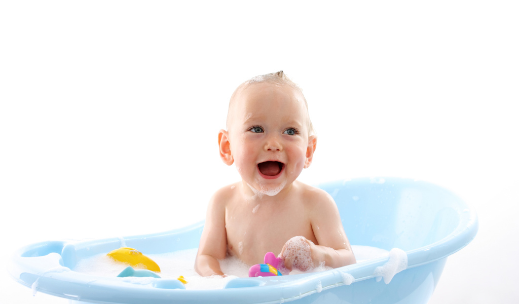 Улыбающийся грудной ребенок сидит в синей ванночке на белом фоне