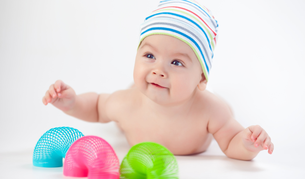 Улыбающийся грудной ребенок с игрушками радуга