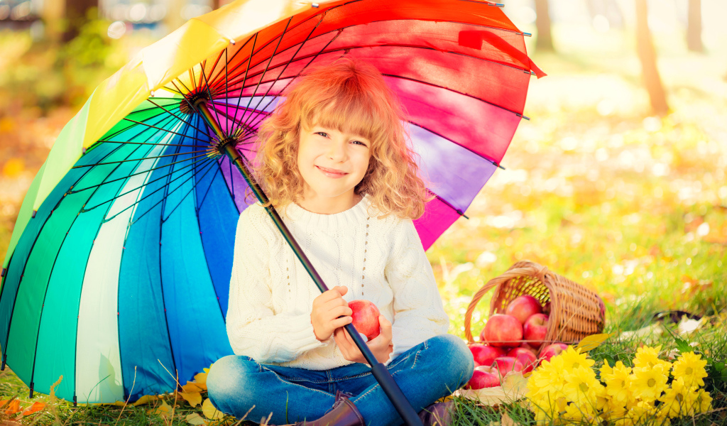 Улыбающаяся девочка под сидит под разноцветным зонтом