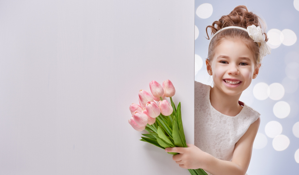 Улыбающаяся маленькая девочка с букетом розовых тюльпанов
