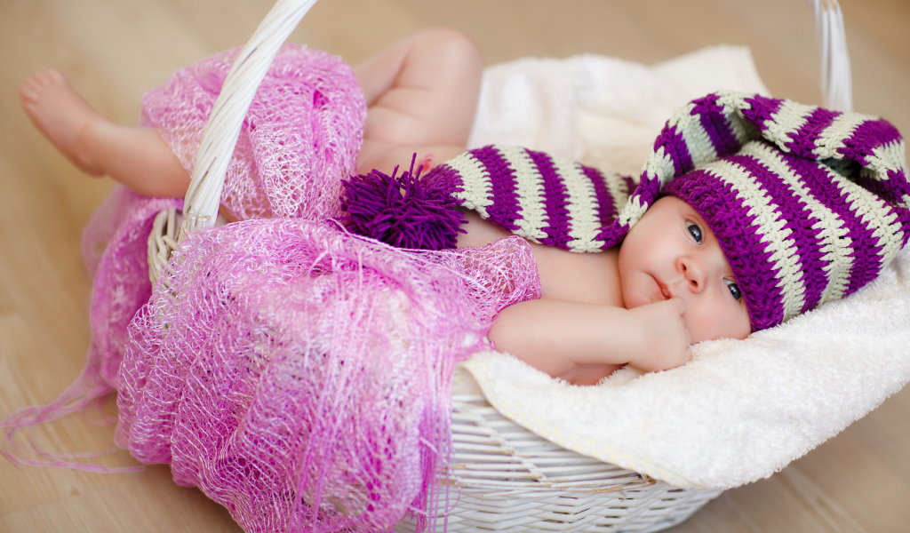 Младенец в красивой вязаной шапке лежит в корзине