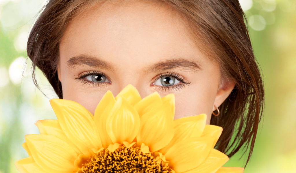 Взгляд маленькой девочки шатенки с подсолнухом в руках