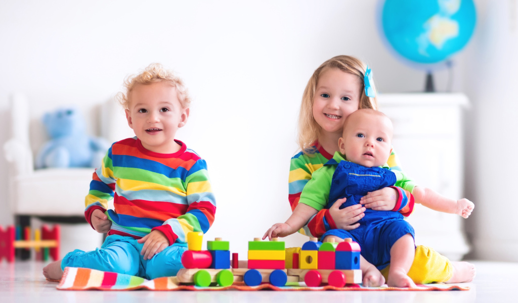 Три ребенка играют с игрушечным поездом