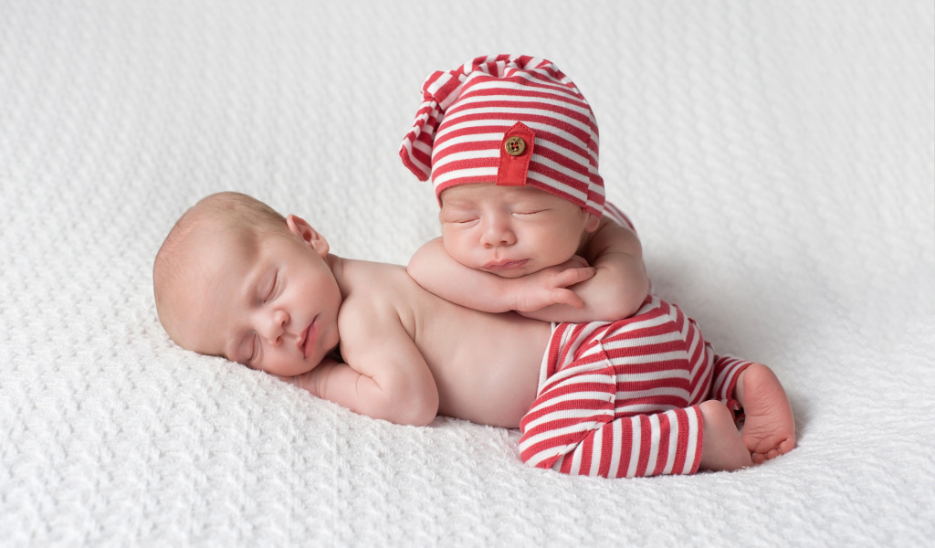 Два милых спящих младенца в полосатых костюмах