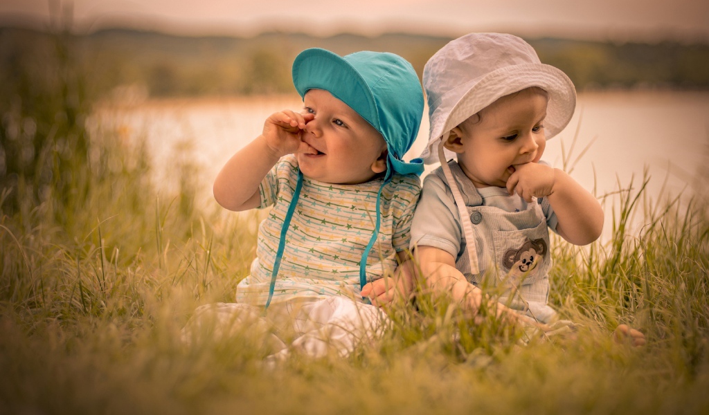 Два милых малыша в зеленой траве летом 