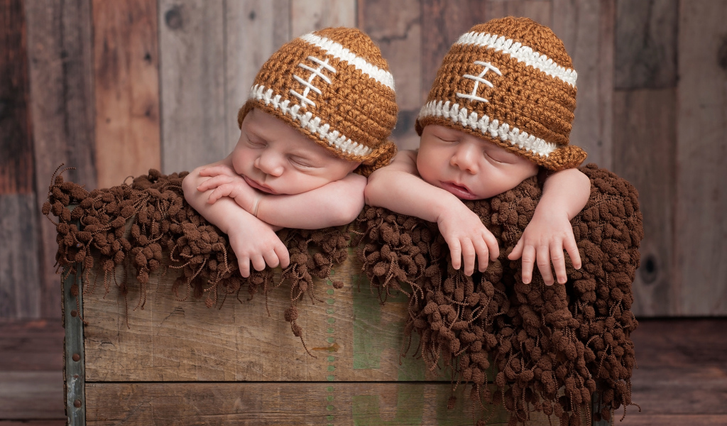Два милых спящих малыша в забавных вязаных шапках