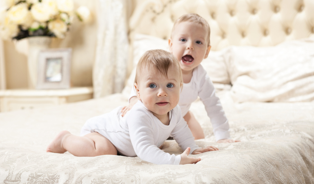 Два забавных младенца лежат на кровати