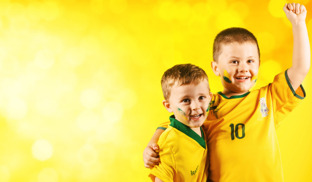 Два маленьких мальчика в спортивной форме на желтом фоне