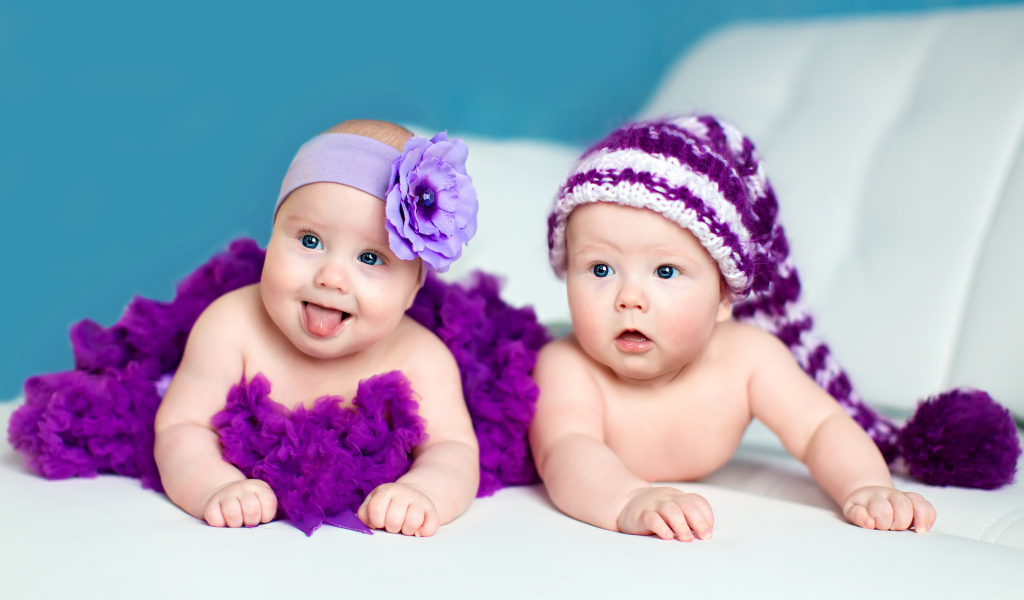 Два маленьких забавных младенца в красивых фиолетовых костюмах