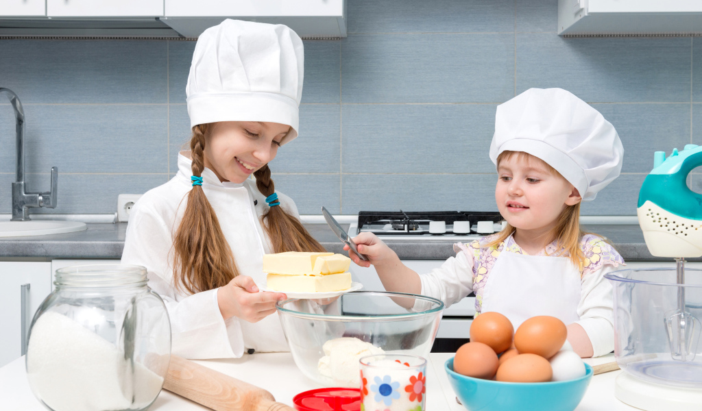 Две маленькие девочки на кухне готовят пирог