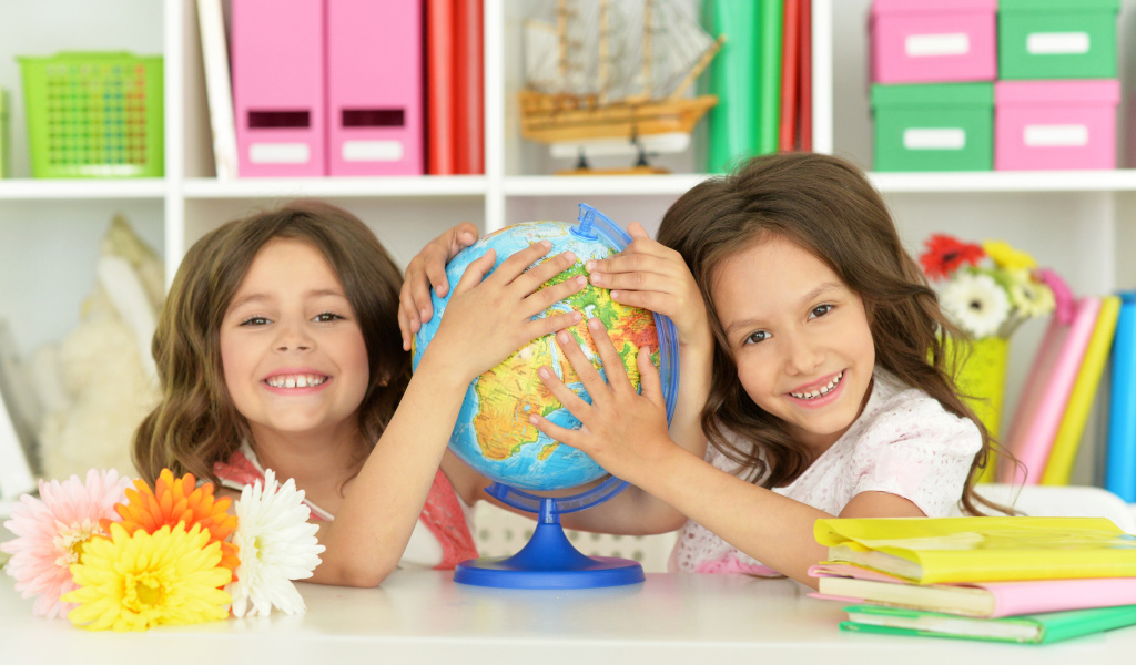 Две маленькие девочки школьницы с глобусом  в руках