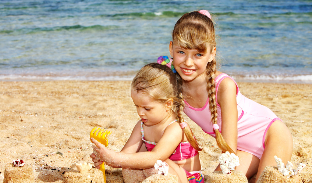 Две маленькие девочки гуляю на песке на пляже
