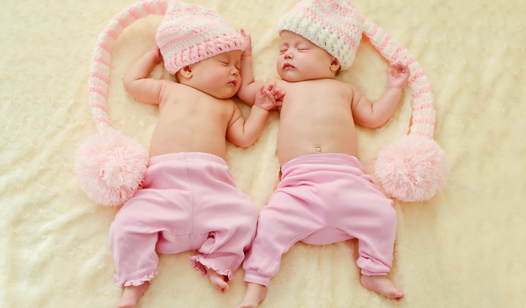 Два спящих грудных ребенка в розовых костюмах