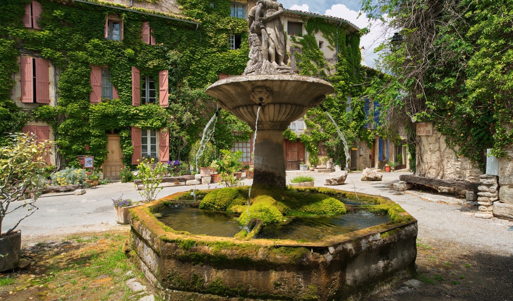 Старинный покрытый мхом фонтан на площади Сеньон, Франция