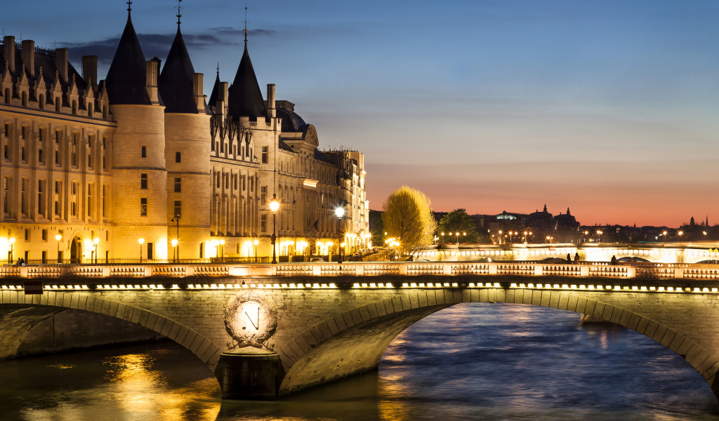 Мост в свете ночных фонарей у бывшего королевского замка Консьержери, Париж. Франция 