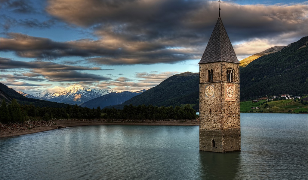 Старинная часовня на фоне красивого неба посреди озера Резия, Италия