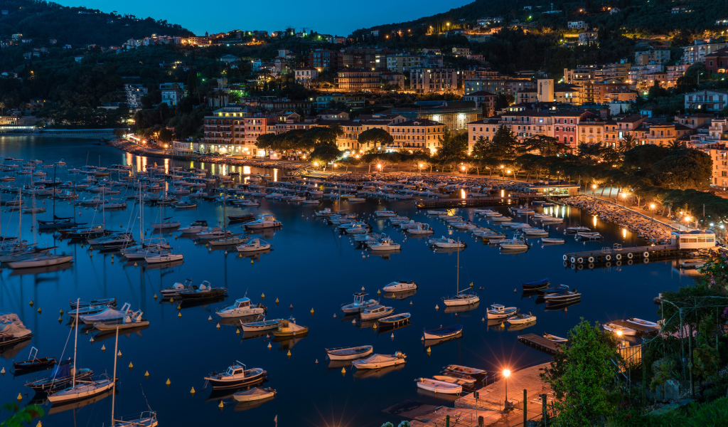Панорама ночного города и лодки на причале у побережья, Лигурия. Италия