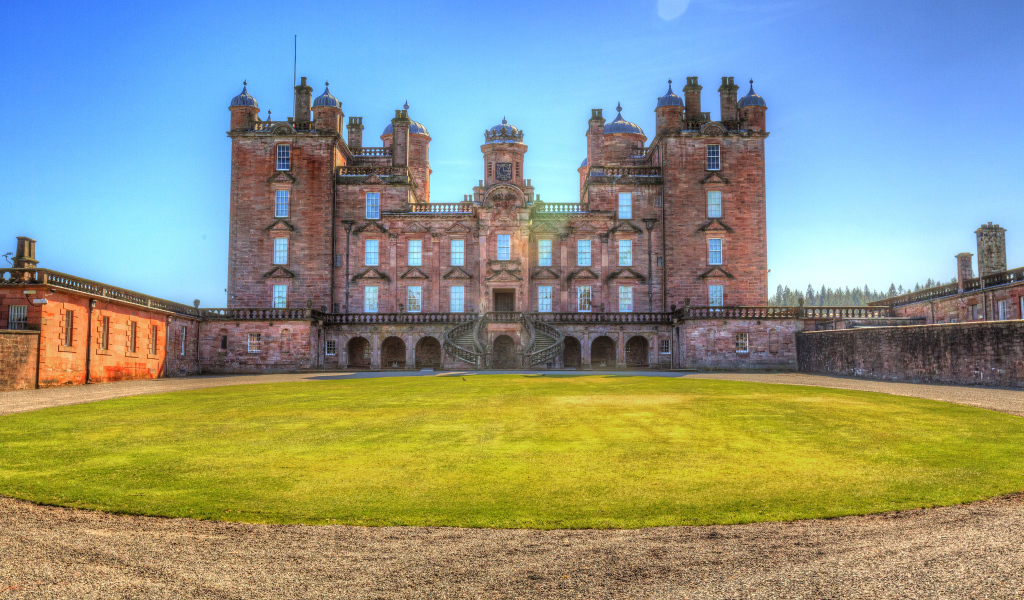 Замок Drumlanrig Castle с зеленым  газоном, Шотландия 