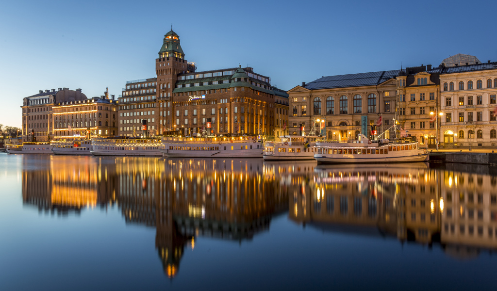 Красивые дома отражаются в воде у причала вечером, Стокгольм. Швеция