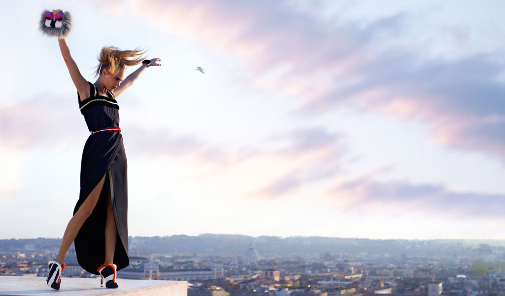 Актриса Кара Делевинь в черном платье на фоне неба 