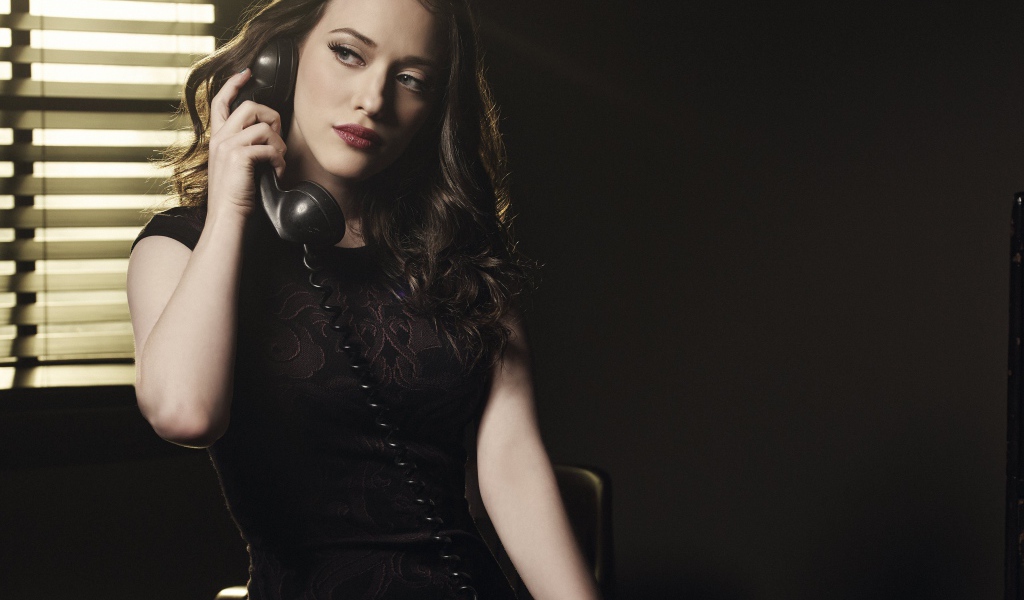 Актриса Кэт Деннингс в черном платье с телефоном в руках