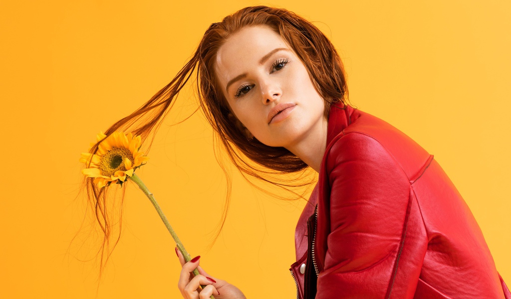 Актриса Мэделин Петш в красной куртке фото на оранжевом фоне