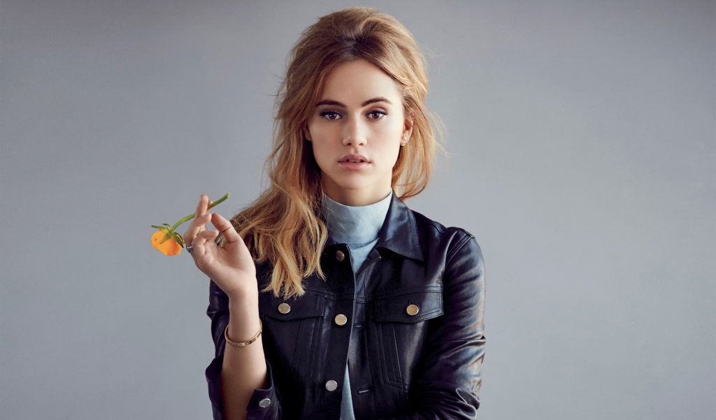 Актриса Сьюки Уотерхаус с цветком в руках на сером фоне