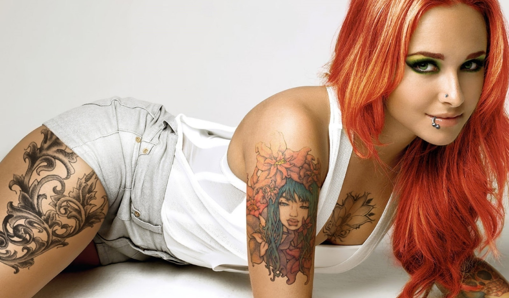 Красивая рыжеволосая девушка с пирсингом и татуировками