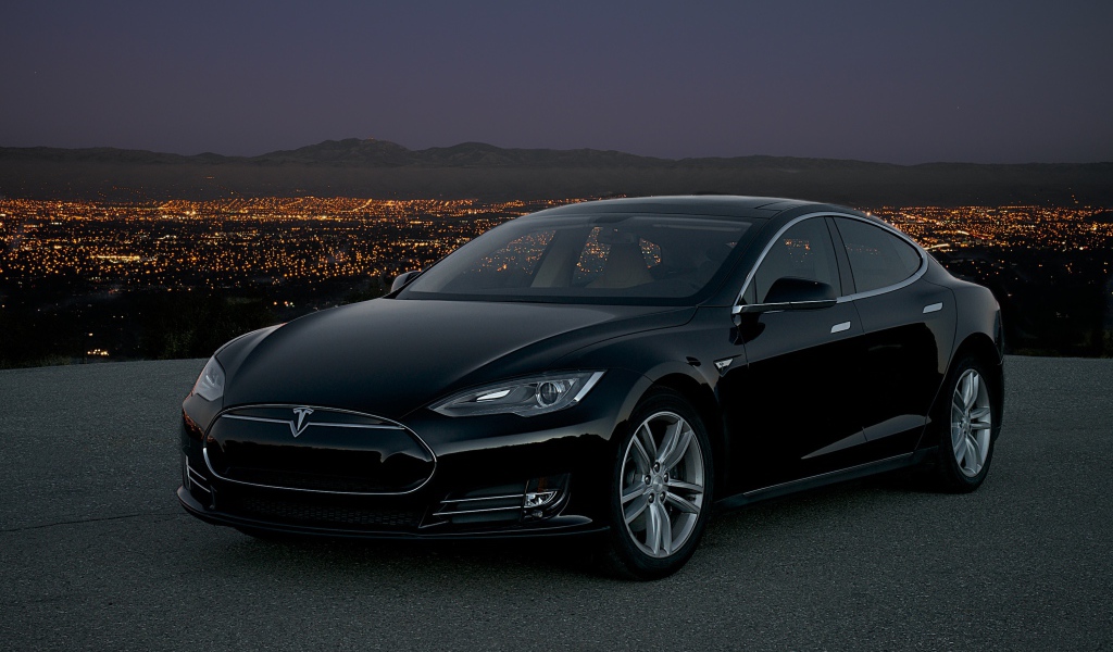 Черный стильный электромобиль Tesla Model S на фоне ночного мегаполиса 