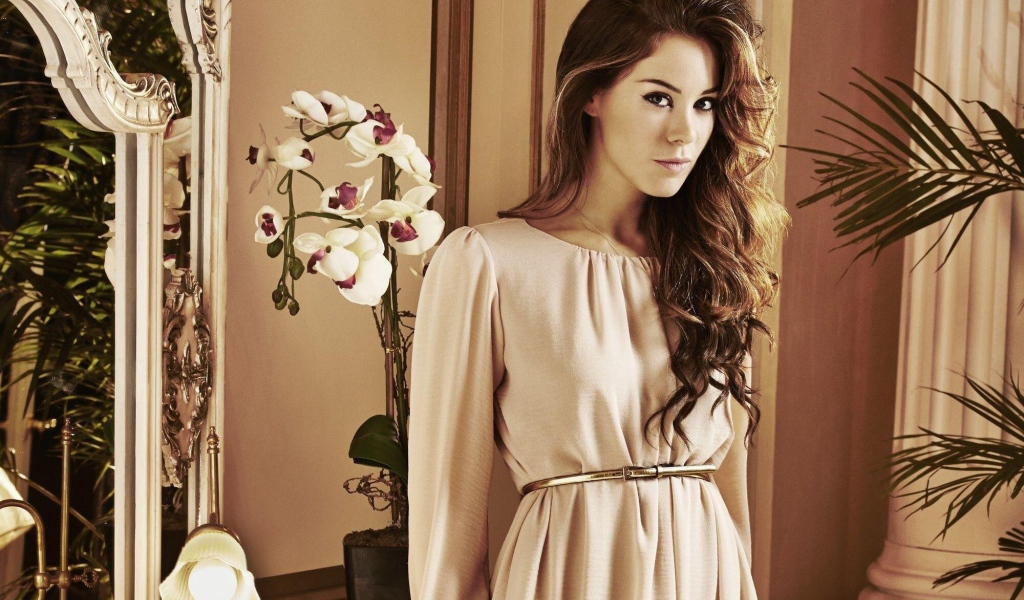 Брюнетка актриса Роксанна Макки стоит рядом с цветком орхидеи