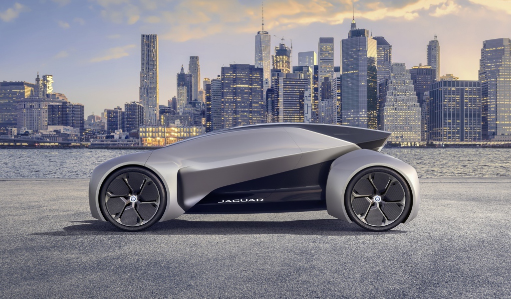 Серебристый электрический автомобиль  Jaguar Future-Type на фоне небоскребов