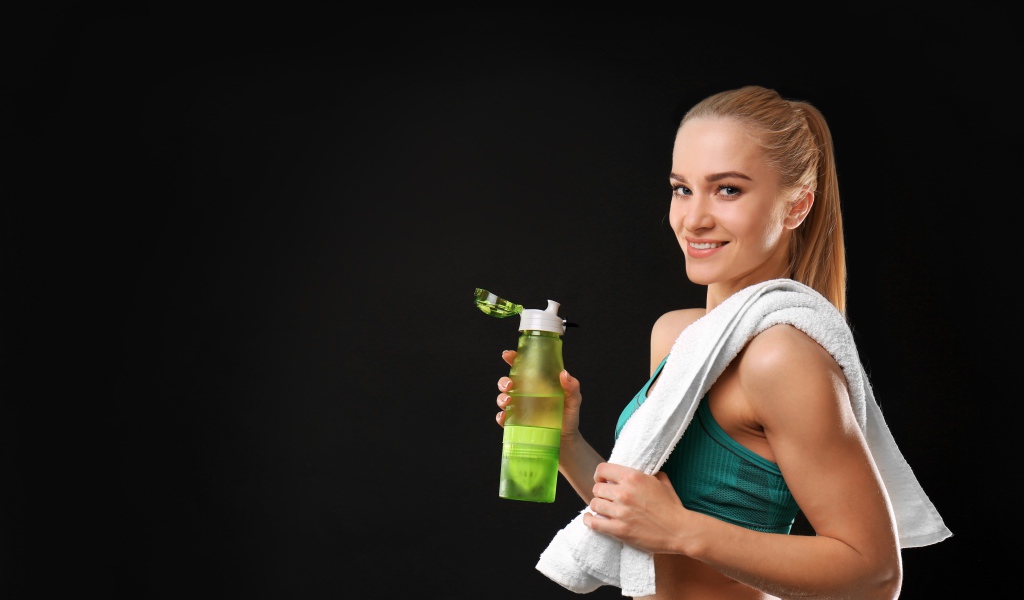 Спортивная девушка блондинка с бутылкой воды в руке