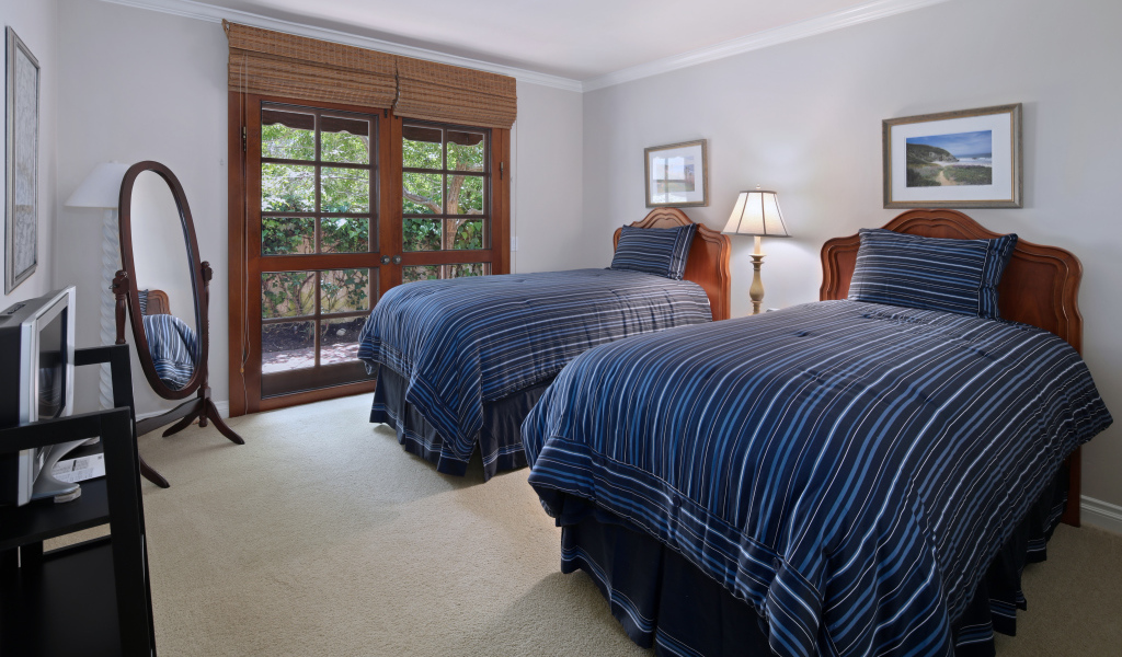 Две большие кровати в спальне с деревянным окном