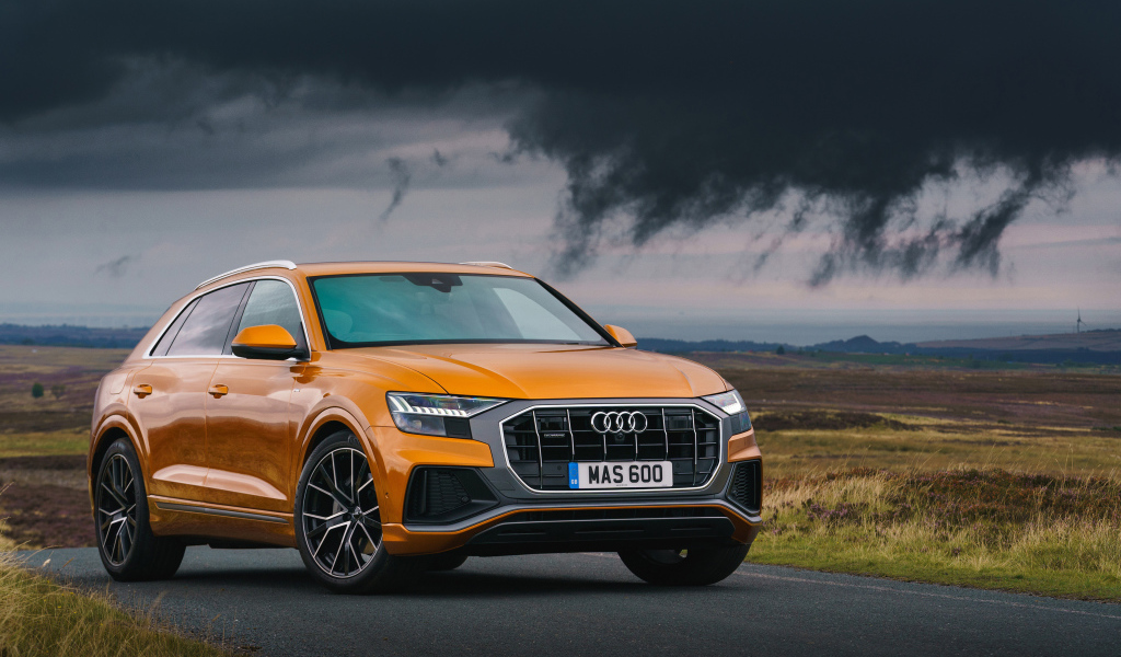 Orange car Audi Q8, 2018 on the background of a stormy sky