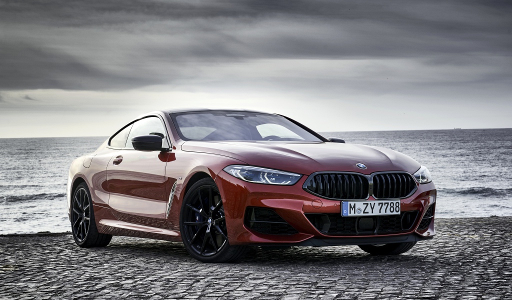 Красный автомобиль BMW 8 Series на фоне моря