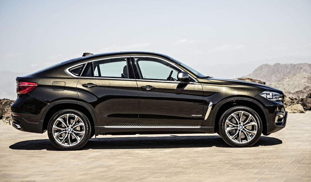 Черный автомобиль BMW X6, 2018 года вид сбоку